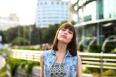 Genç esmer kız açık havada poz kot yelek