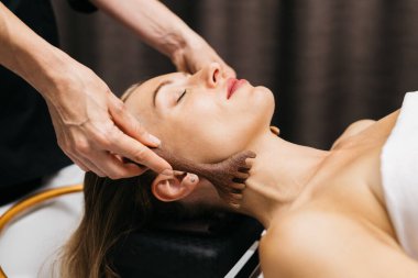 Kadın, sakin bir spa ortamında, rahatlatıcı bir yüz masajı, rahatlama ve kendine dikkat çekme, yumuşak ışıklandırma ve huzurlu bir atmosfer ile deneyimi geliştirmekten hoşlanıyor.