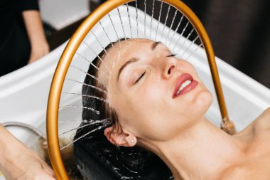 Sakin bir spa ortamında hidroterapi gören bir kadın, kafasının etrafında yavaşça akan su, yenilikçi su masajı teknikleri ve rahatlatıcı ambiyansla rahatlama ve sağlığını arttırıyor.