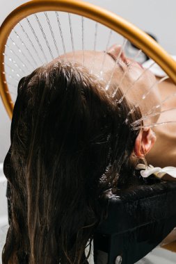 Su jetleri rahatlatıcı bir kafa masajı yaparken kadınlar hidroterapi seanslarından zevk alıyor, sakin spa atmosferini vurguluyor ve su terapisinin rahatlama ve iyileşme üzerindeki canlandırıcı etkilerini vurguluyor.