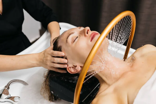 Kadın, sakin bir spa ortamında hidroterapiden hoşlanır. Kafasının üzerinden yumuşak su akar, rahatlatıcı su masajı teknikleri ve dingin ortam yoluyla rahatlık ve sağlığını arttırır.