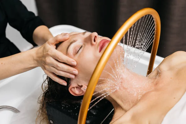 Kadın, sakin bir spa ortamında yapılan hidroterapi seanslarından zevk alıyor. Kafasının etrafında yumuşak su akıyor. Sakinleştirici su masajı deneyimleri sayesinde rahatlık ve sağlığını arttırıyor.