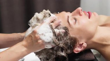 Kadın kuaförde saçlarını yıkarken dinleniyor.