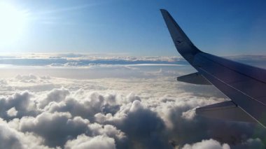 Kabarık beyaz bulutların üzerinde uçan uçak kanadı