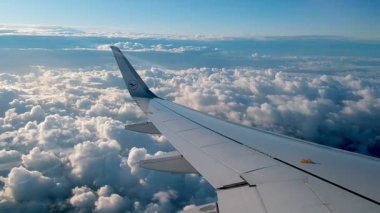 Kabarık beyaz bulutların üzerinde uçan uçak kanadı