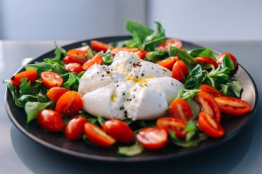 Çeri domateslerin arasında duran taze burrata peyniri.