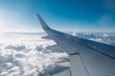 Airplane wing extends over soft clouds, showcasing a vibrant blue sky, evoking feelings of freedom and exploration in the vastness of the atmosphere