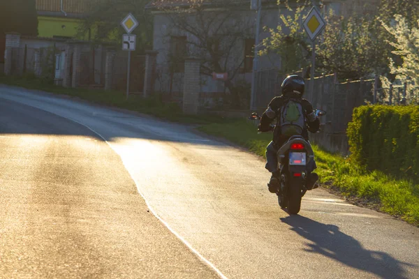 bir adam bir köyde bir şehir güneşli yolu üzerinde bir gölge ışık tarafından spor motosiklet sürmek
