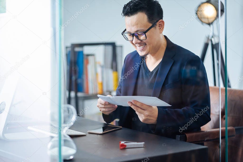 Asian businessman receive a letter with good news in a office .