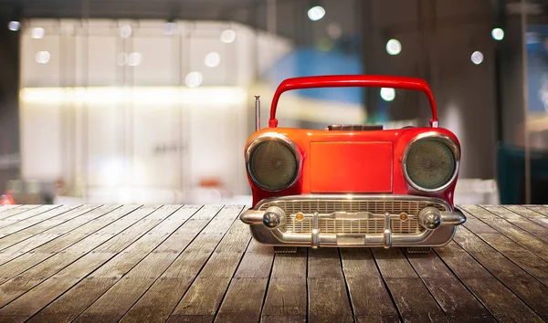 Old antique car shape AM FM stereo cassette player on wood table top with blur background