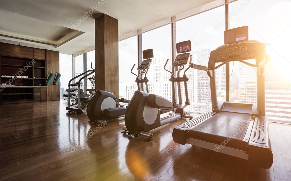 Modern gym room fitness center with set of treadmills staying in line , morning sunrise  scene .