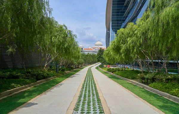 緑の草と近代的な建物の背景を持つ公園内の石の散歩道 — ストック写真