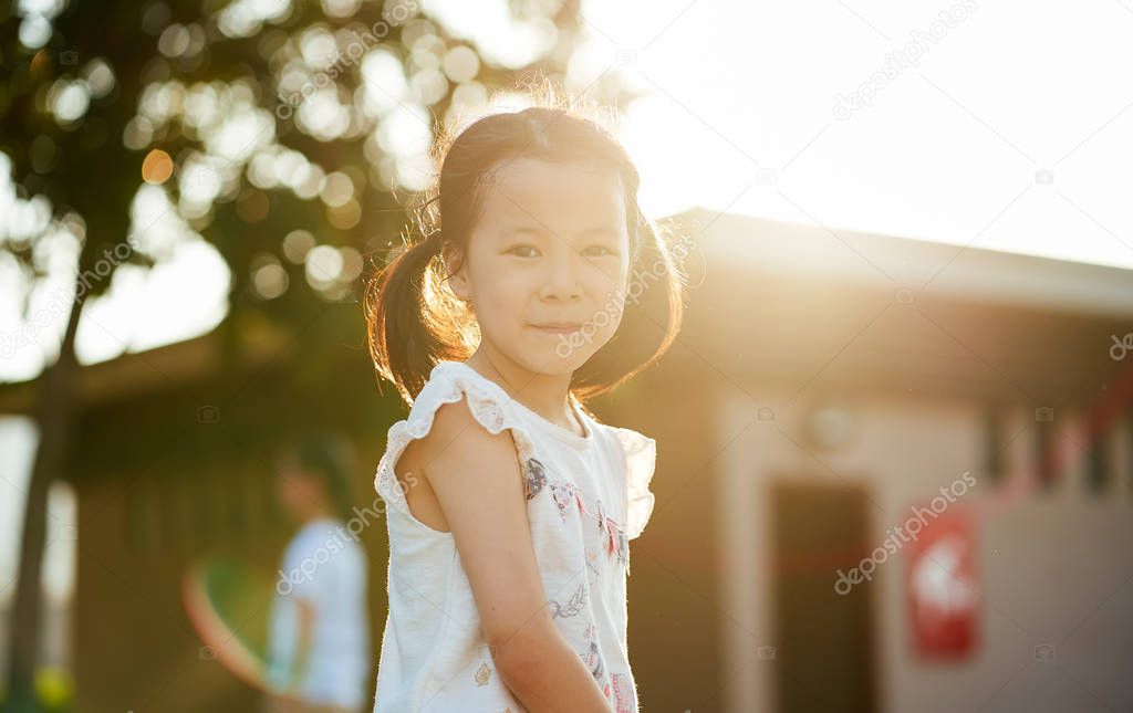 Outdoor portrait of little asian girl with dimples in park during sunset