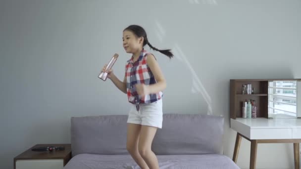 快乐的亚洲小女孩 唱着歌 跳着上床 假装梦想着在一天内成为歌手 慢动作高清 — 图库视频影像