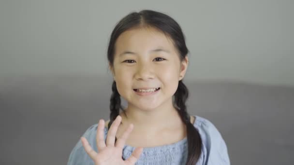 Aranyos Ázsiai Kislány Mosolyog Integet Kezét Nézi Kamera Otthon — Stock videók
