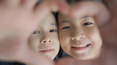 Mutlu kız kardeş kalp şeklinde el hareketi yapar, aşk ve dostluk sonsuza dek konsept, yakın açı