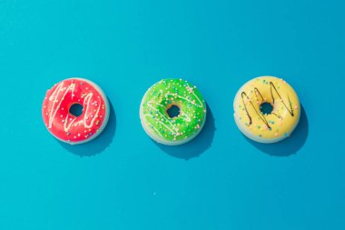 Pastel mavi arka plan, çok az gıda kavramı üzerinde renkli Donuts yaratıcı düzenleme