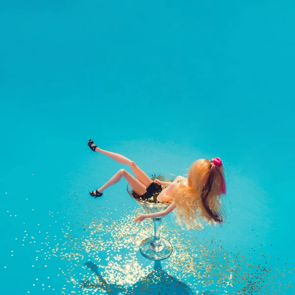 娃娃沐浴在马提尼玻璃充满金色的闪光在蓝色背景 创意极小的美丽夏日概念 — 图库照片