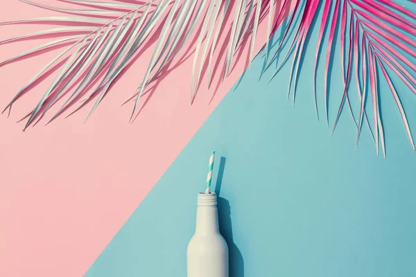 Painted palm leaves and cold drink on pastel pink and blue background, Tropical summer concept