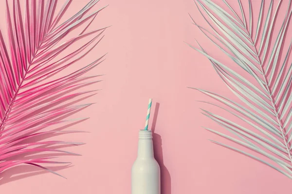 Painted palm leaves and cold drink on pastel pink background, Tropical summer concept