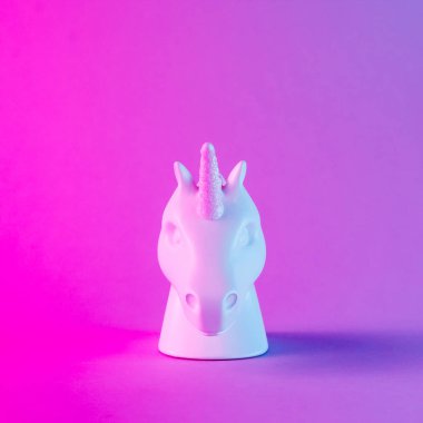 Beyaz tek boynuzlu at kafası degrade arka plan üzerinde koyu pembe ve mavi neon renklerde boyanmış. Minimal sanat fantezi kavramı.