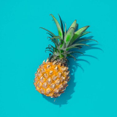 Ananas ve mavi parlak kağıt ile yaratıcı tropikal düzeni. Soyut gıda sanat arka plan. En az yaz konsepti. Düz yatıyordu.