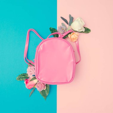 En az pastel pembe ve mavi arka plan, başa okul moda kavramı üzerinde renkli çiçekli pembe okul çantası
