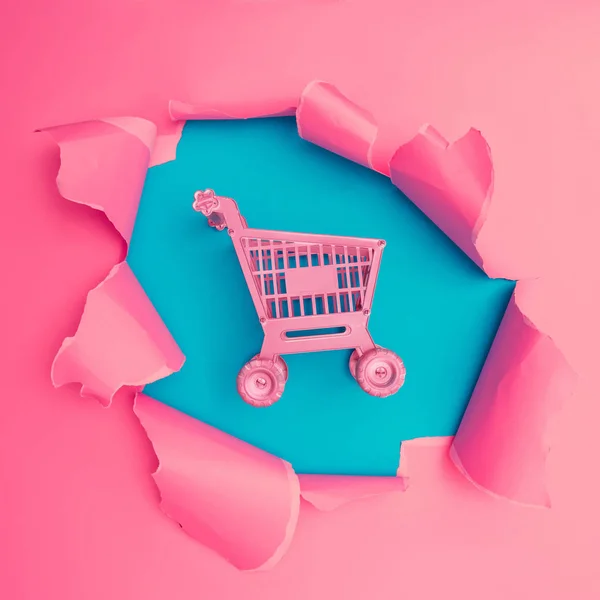 购物车在爆裂孔的生动的粉红色撕裂纸 最小抽象多彩墙纸概念 — 图库照片