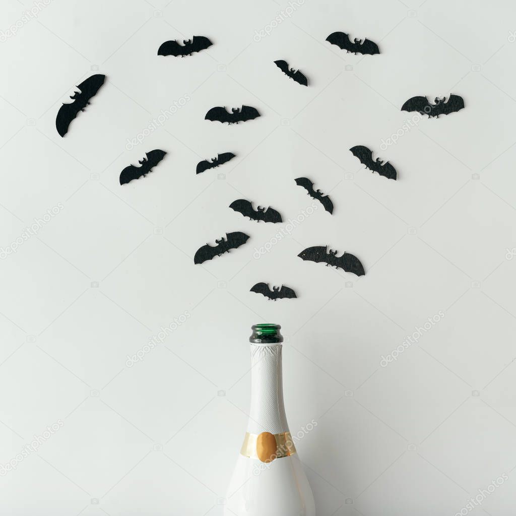 Champagne bottle with bats silhouettes on white background. Flat lay. Halloween party concept.