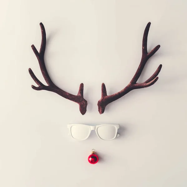 用白色太阳镜和红色新年摆设装饰的鹿角制成的圣驯鹿 最小冬季假期概念 — 图库照片