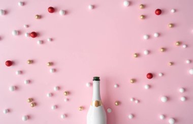Pembe bir arka plan üzerinde şampanya şişesi ve glitter dekorasyon topları ile yeni yıl tebrik kartı. En az tarzı. Düz yatıyordu kompozisyon.
