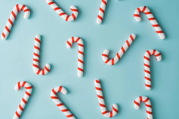 Pattern composition of red and white candy cones on pastel blue background. Minimalist isometric christmas concept