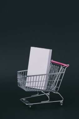 Alışveriş sepeti içinde beyaz kutu ile yaratıcı koyu arka plan. 