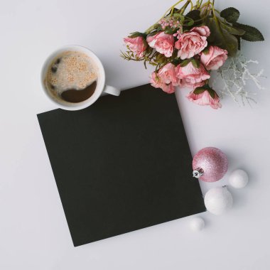 Çiçekler ve kahve fincanı kağıt kartı ve tablo, üstten görünüm pembe Noel topları ile yaratıcı kış doğal kompozisyonu. 