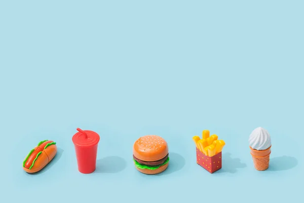 Fast food items on pastel blue background. Junk food minimal concept