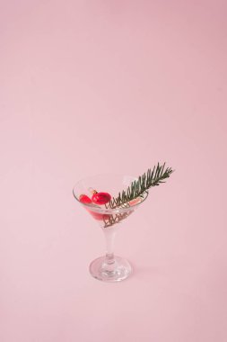 Martini cam pastel pembe arka plan, yeni yıl arifesinde parti kavramı üzerinde Noel ağacı süsle 