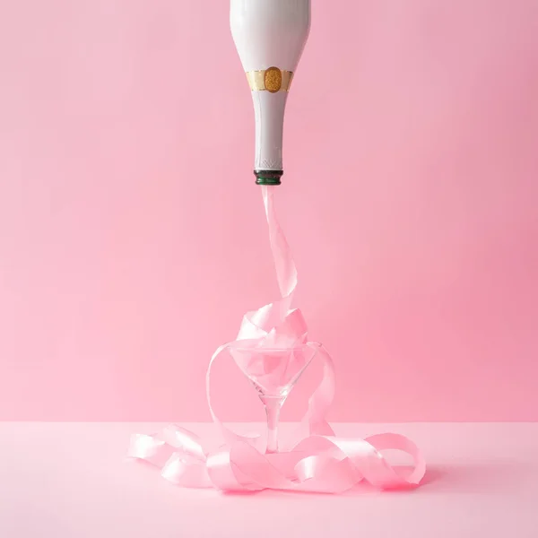 pink party ribbon pouring from champagne bottle in glass. Minimal Celebration concept