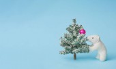 Jegesmedve toy Christmas tree és a labda dísz, fényes pasztell kék háttér. Karácsony és téli ünnepek koncepció.