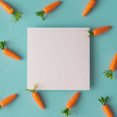 Parlak mavi arka planda havuç ve kağıt kartı notu ile yapılan Paskalya deseni. Yaratıcı minimal tatil konsepti 