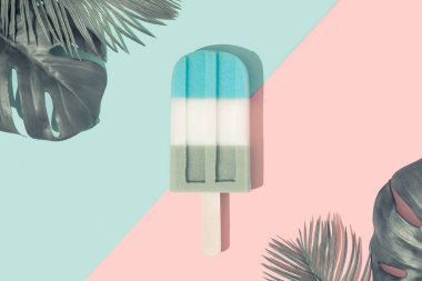 Kağıt duotone arka plan üzerinde tropikal palmiye yaprakları ile pastel mavi renkte dondurma popsicle . Minimal yaz konsepti 