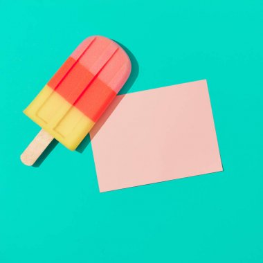 Canlı mavi arka plan üzerinde pembe kağıt kart notu ile dondurma popsicle. Minimal yaz kompozisyonu 
