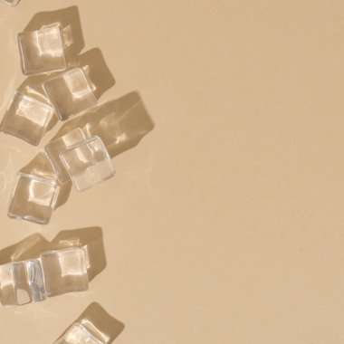 Kumlu pastel renk arka plan üzerinde buz küpleri ve gölgeler ile Yaz gündüz sahne. Minimal güneş ışığı tropikal düz döşeme düzenleme 