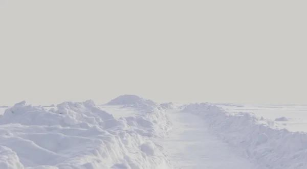 人けのないフィールドで雪に覆われた冬の道の風景 — ストック写真