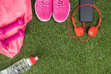 spor şeyler için fitness ile müzik ve bir şişe su yeşil çim üzerinde pembe dizi