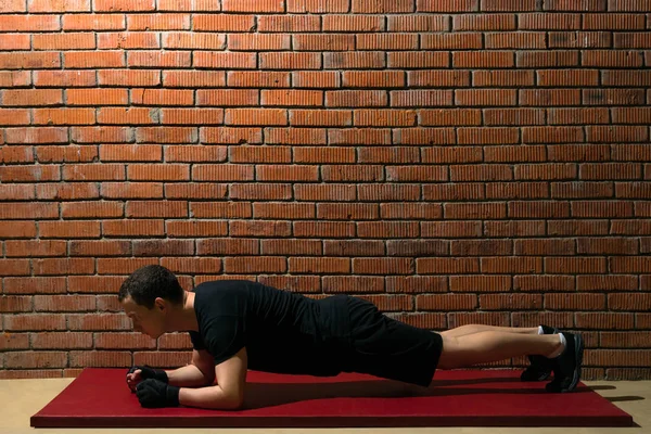 レンガに対してプレスのトレーニングに赤いマットの上 運動を行うホールで選手の壁の背景 — ストック写真