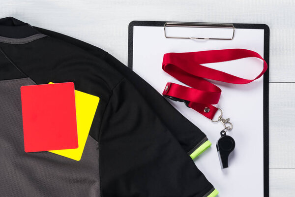 football composition on a light background of a T-shirt, cards of a judge, a tablet for recording and whistle