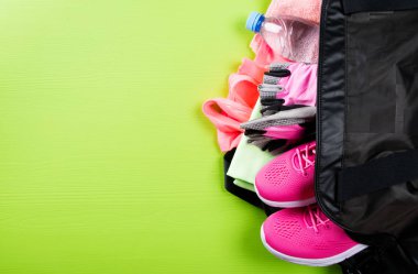 pembe öğeleri fitness ve bir şişe su, açık yeşil arka planı üzerinde siyah bir çanta ile bir yazıt için bir yer