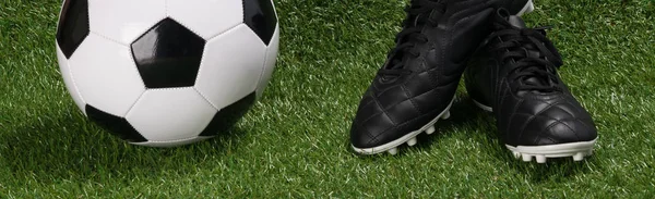 黑色运动鞋和一个球为足球冠军在一个长的绿色草坪 — 图库照片