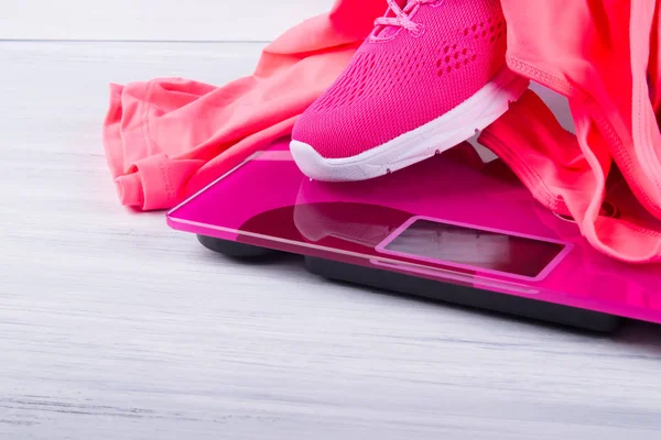pink sneakers and T-shirt, for fitness, on electronic scales, on a gray background