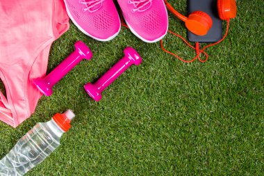 pembe spor ve fitness ve bir şişe su, çim yazmak için bir yer ile arka planda aksesuarlar